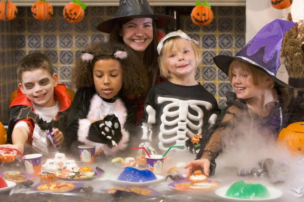 four-young-friends-and-a-woman-at-halloween-eating-treats-and-sm